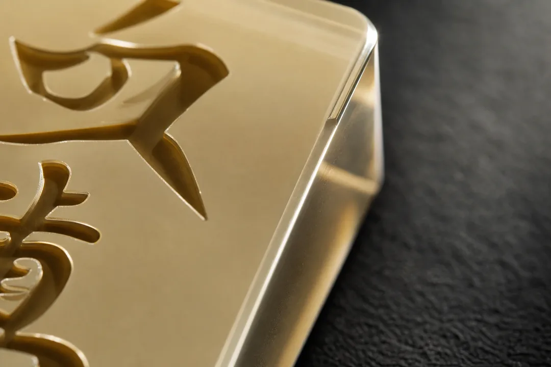 Extreme close-up of acrylic mahjong tile edge showing CNC-chamfered 0.3 mm edge geometry and deep laser-engraved character channel in translucent cast PMMA